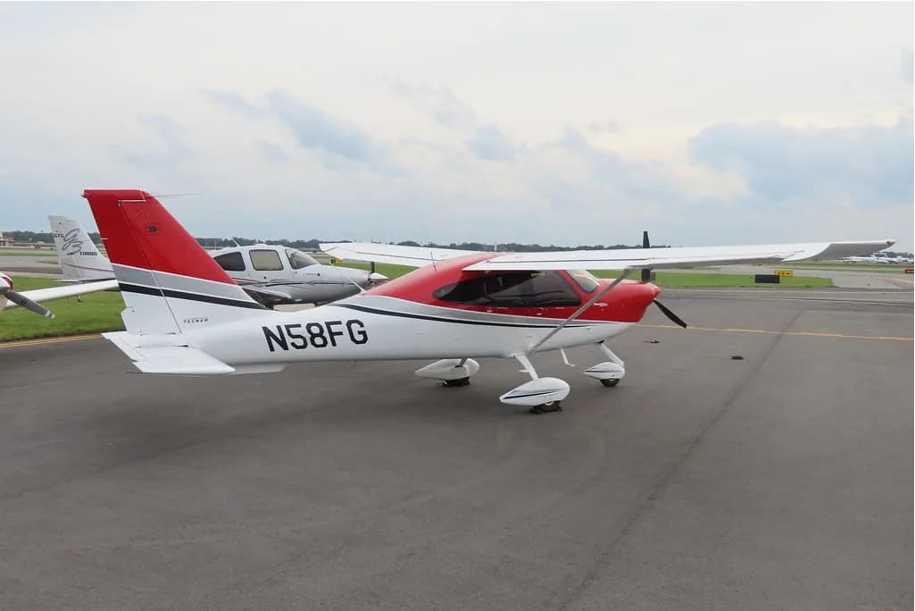 Tecnam P2010 aircraft N58FG parked on the tarmac with a red and white paint scheme.