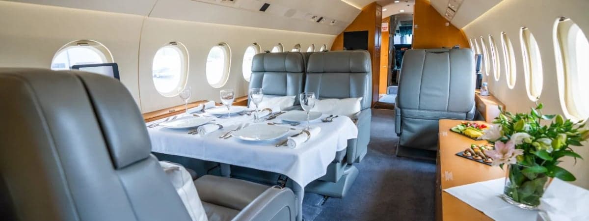 The interior of a private jet with a dining table set for a meal.