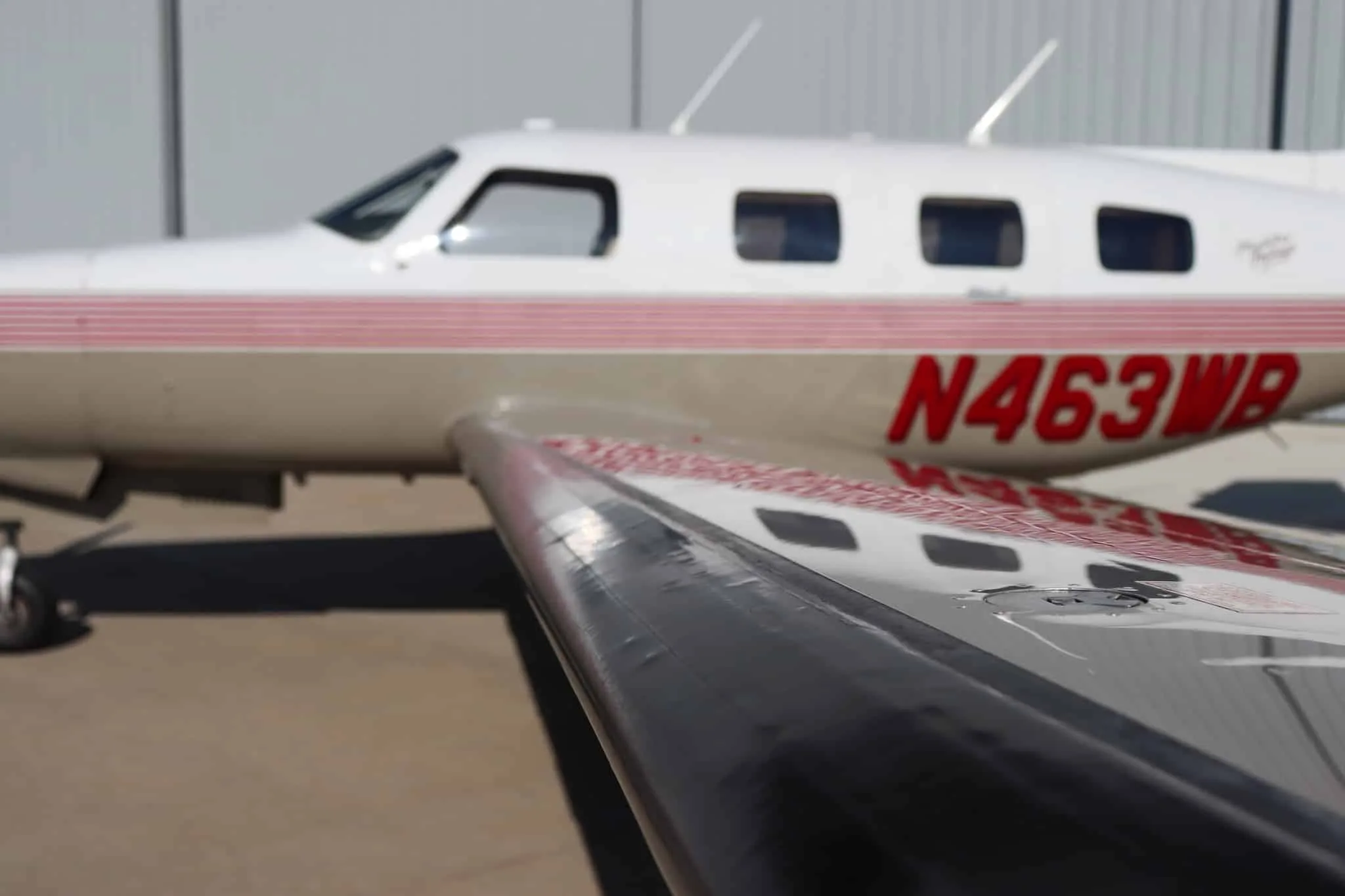 A close-up of the Piper Malibu Mirage N463WB's wing and fuselage, showing the N-number and red stripes.