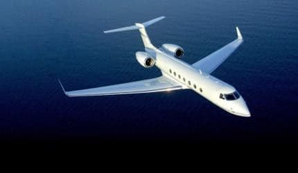 A Gulfstream jet flying over the ocean.