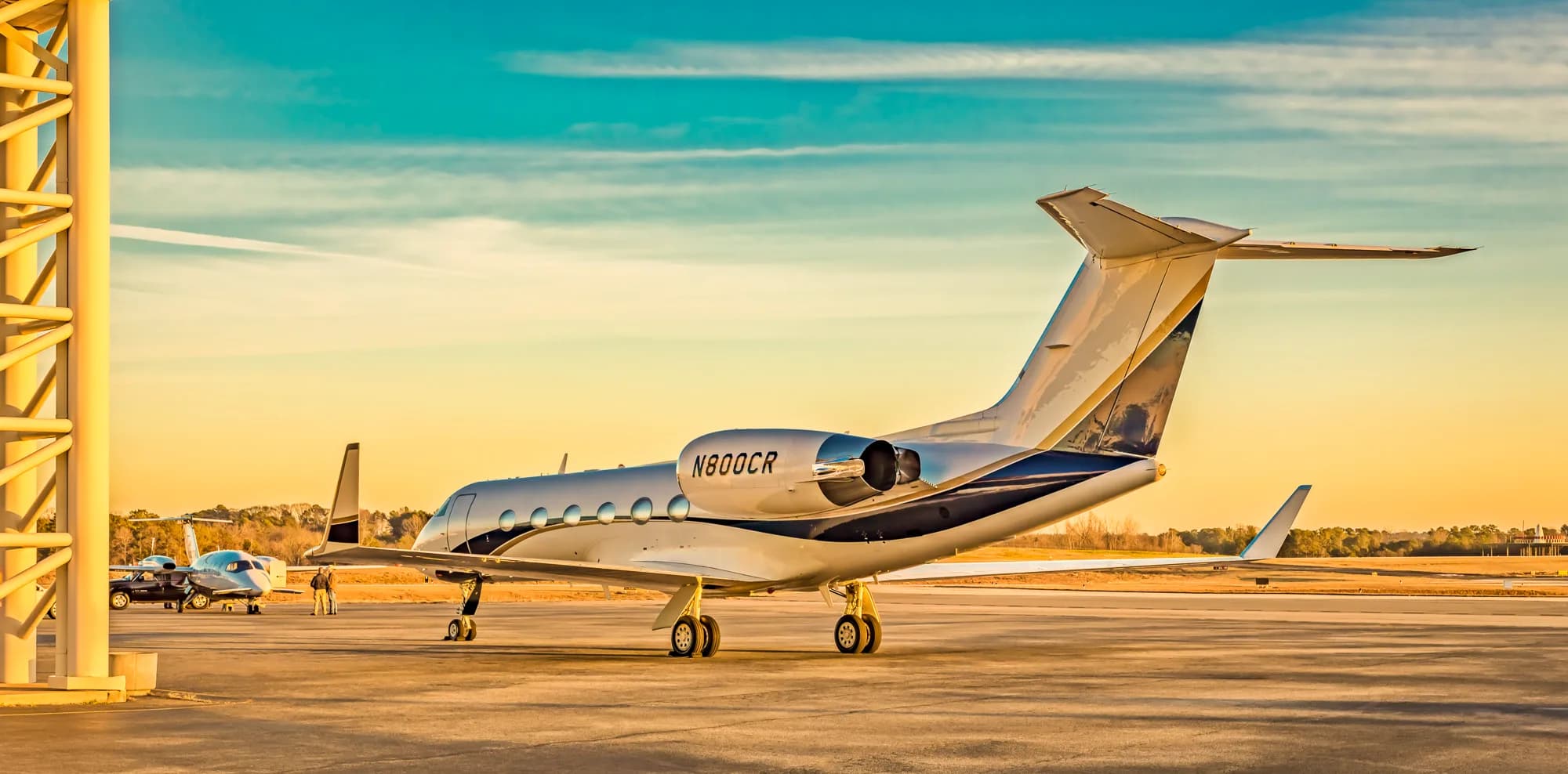 The tail and rear fuselage of a white and blue business jet, N800CR, parked on an airfield at sunset.