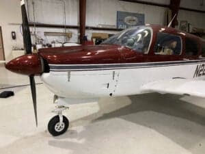 Side view of N2247M's nose and propeller in a hangar setting.