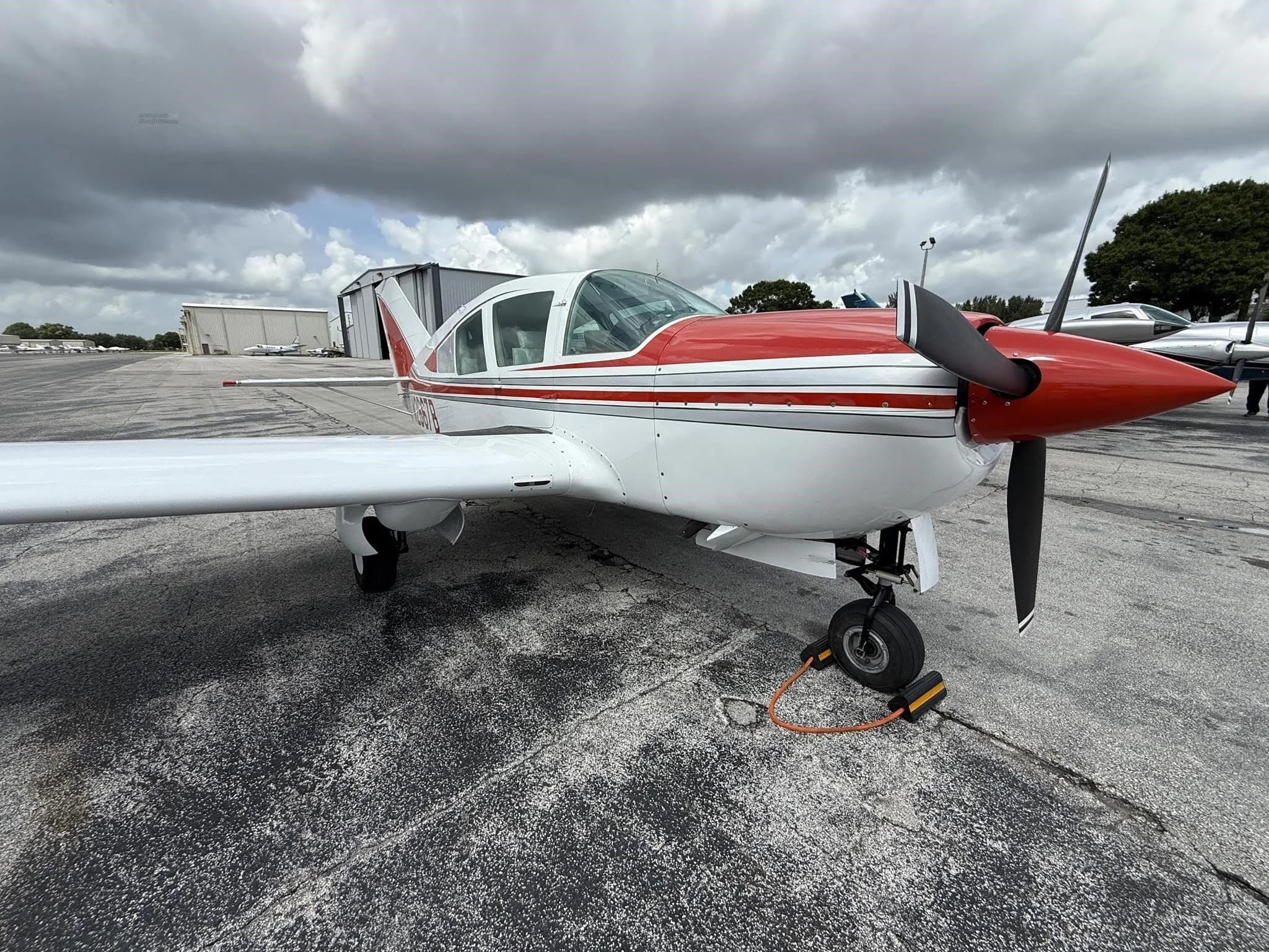 A front-right view of the white and red single-engine aircraft, N2667B, on the tarmac.