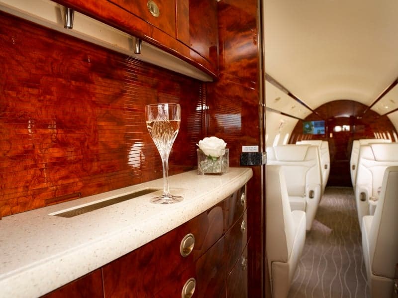 The aircraft's interior features a bar area with a glass of champagne.