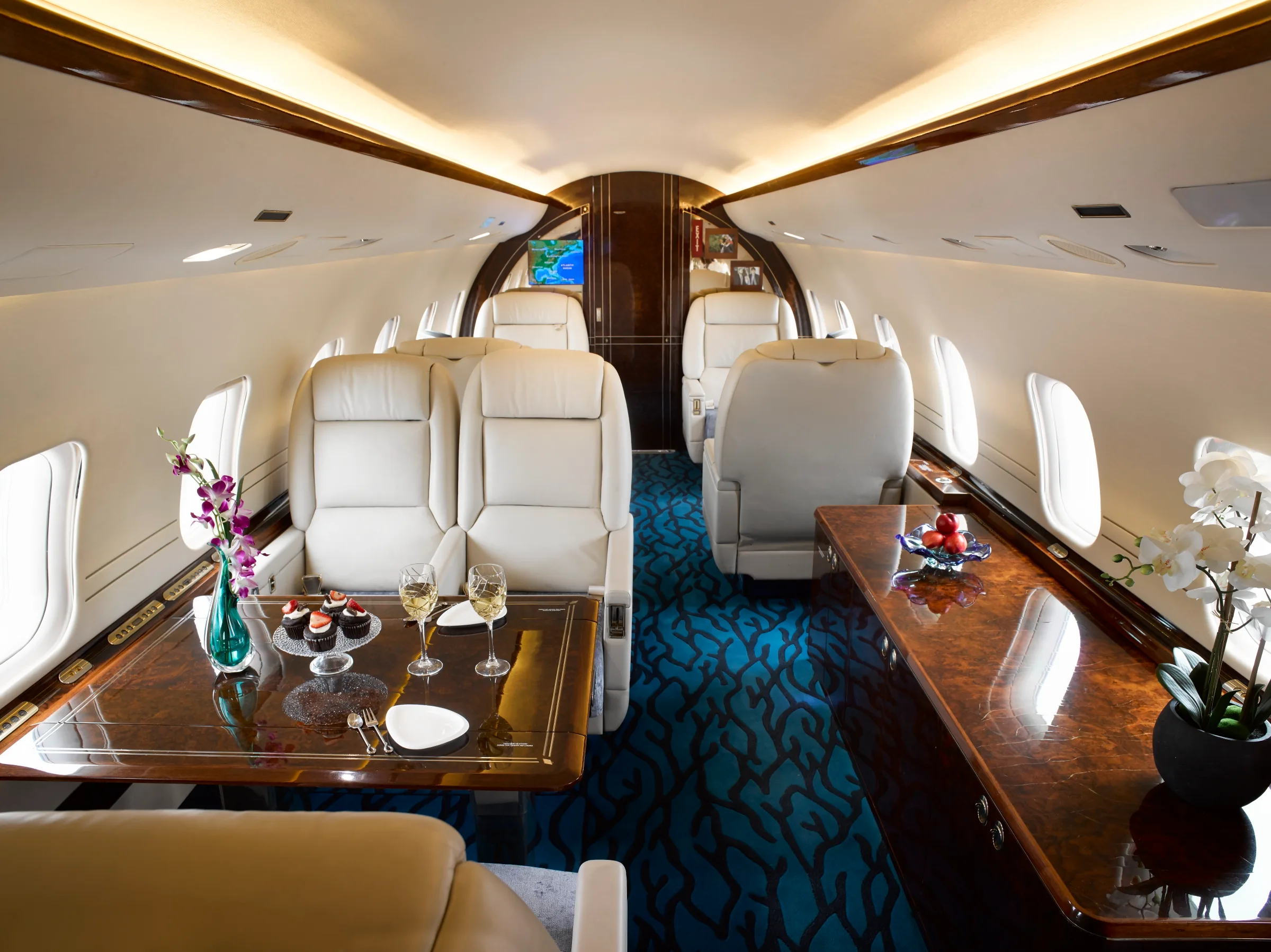 Forward cabin of the aircraft with cream-colored leather seats and wood accents.