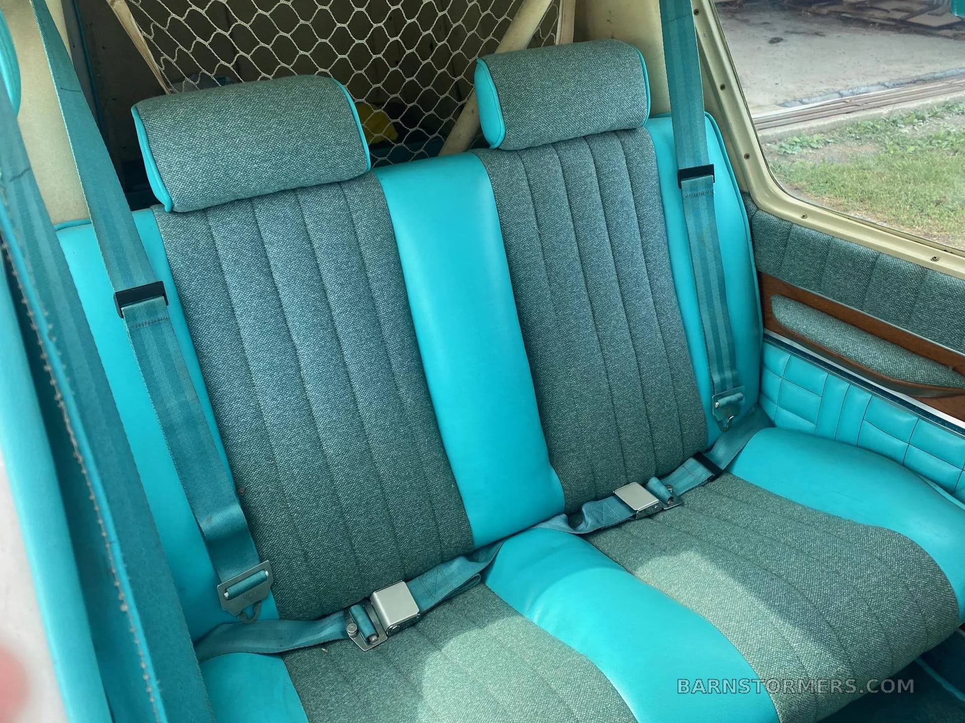 The rear cabin interior of the Bellanca aircraft, showing two blue and grey fabric seats with seatbelts.