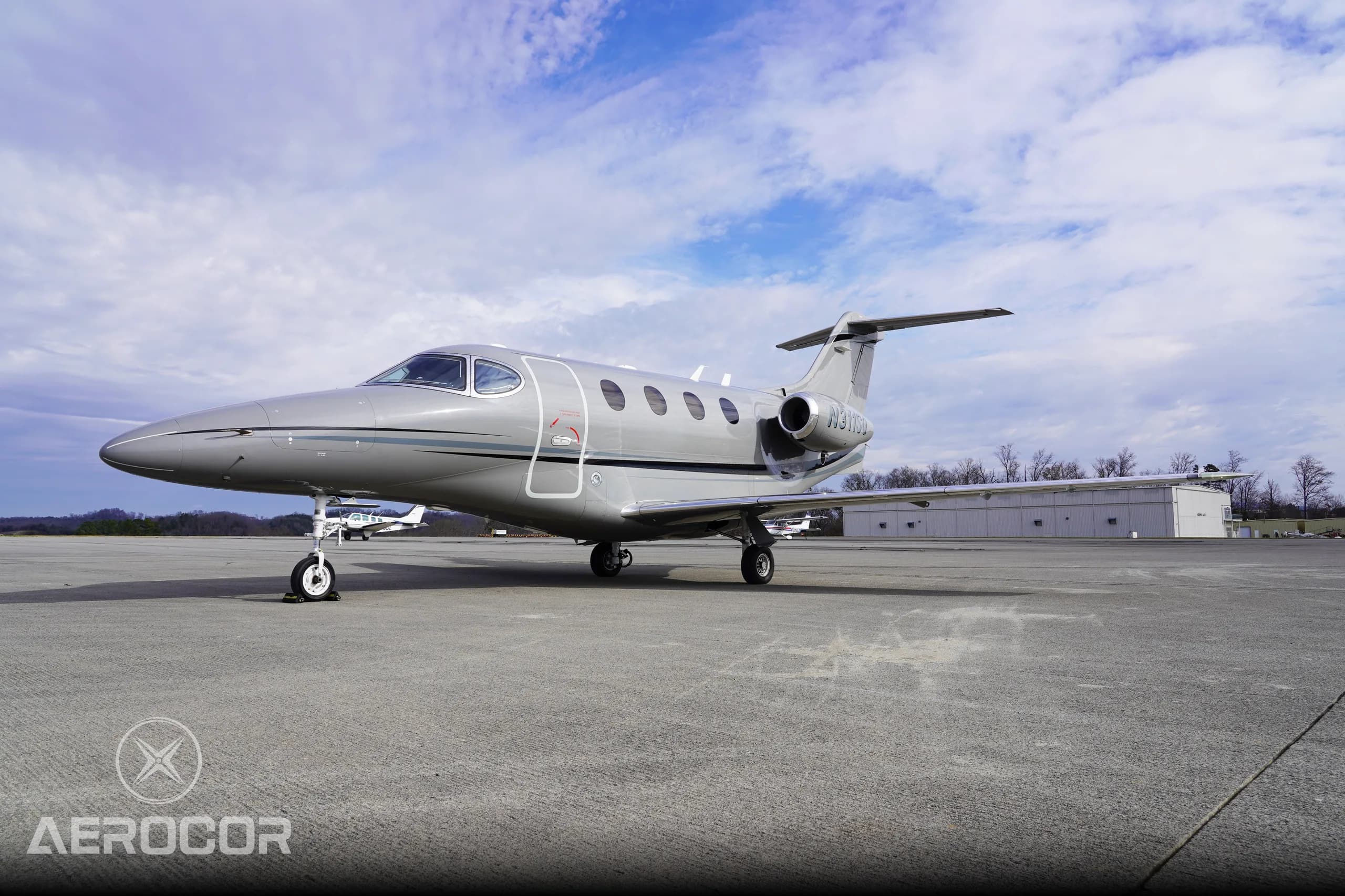 A gray Raytheon Premier I business jet, registration N311SQ, parked on a tarmac with another small aircraft in the background.