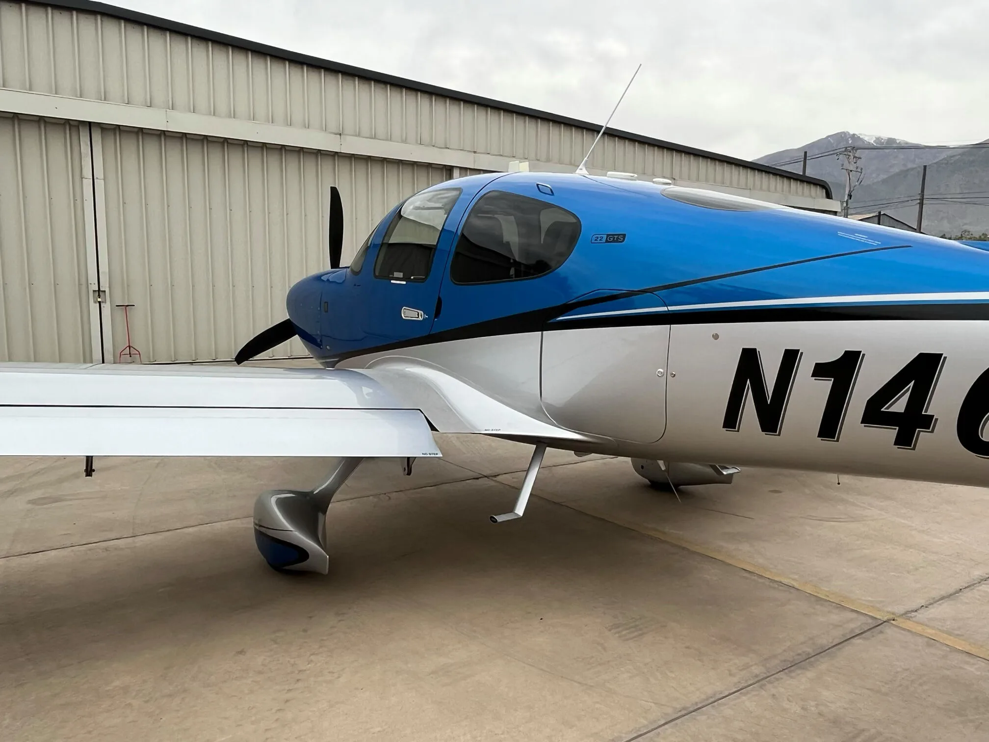 A side profile view of the blue and silver Cirrus SR22 GTS aircraft, showing the N146DM registration.