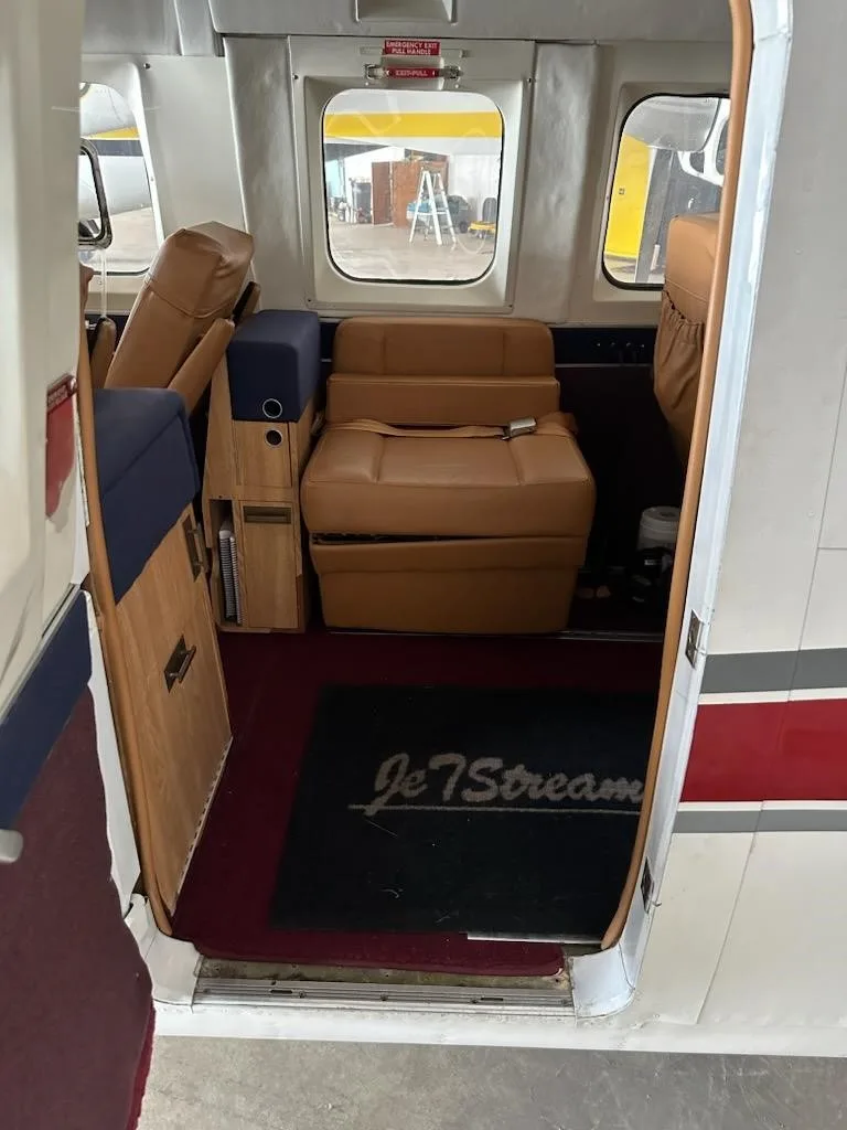A view into the aircraft's cabin interior from the open door, showing tan leather seats and a "JetStream" floor mat.