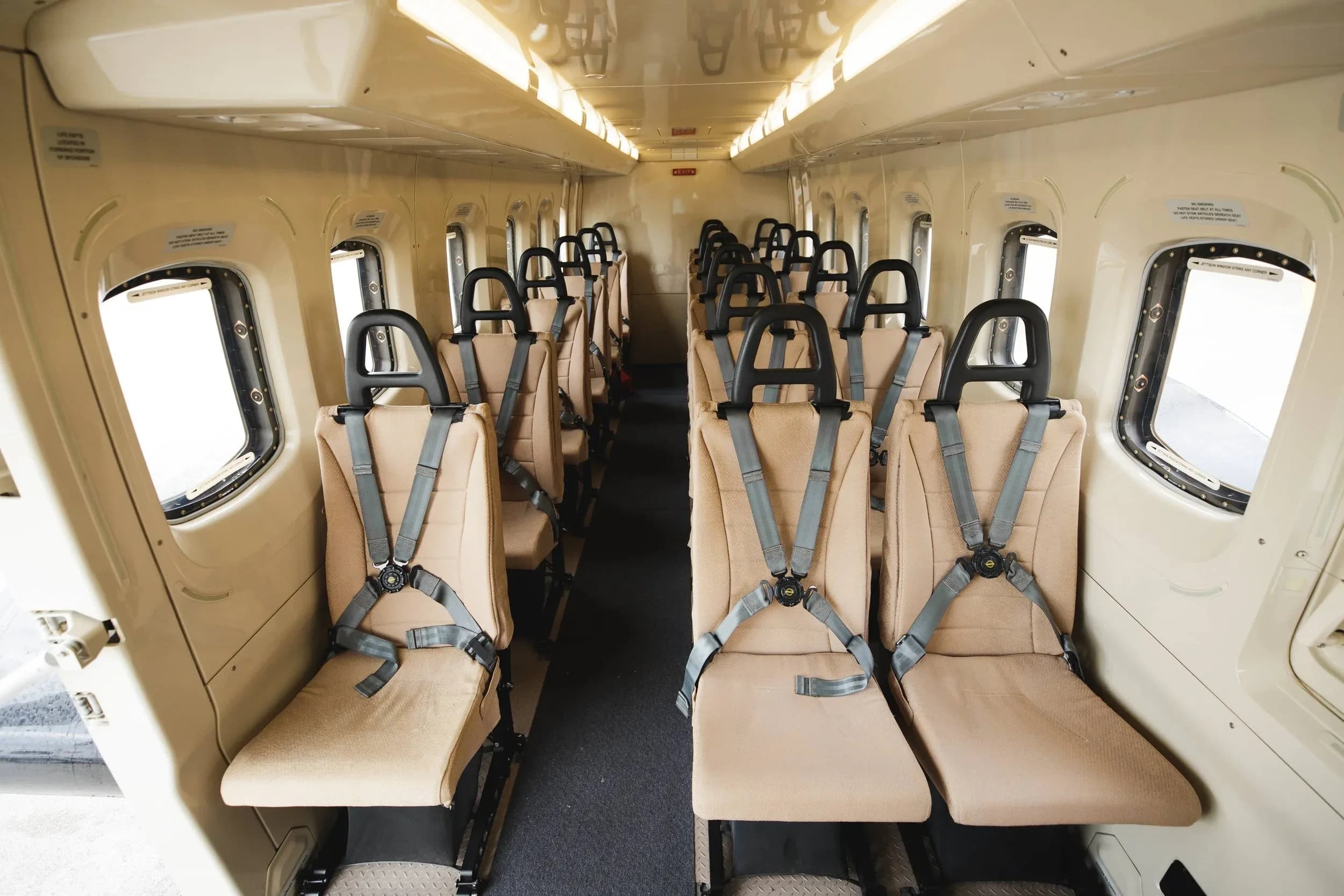 Full view of the helicopter cabin with beige seats and windows.