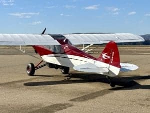 Side view of a red and white Carbon Cub aircraft on the ground.