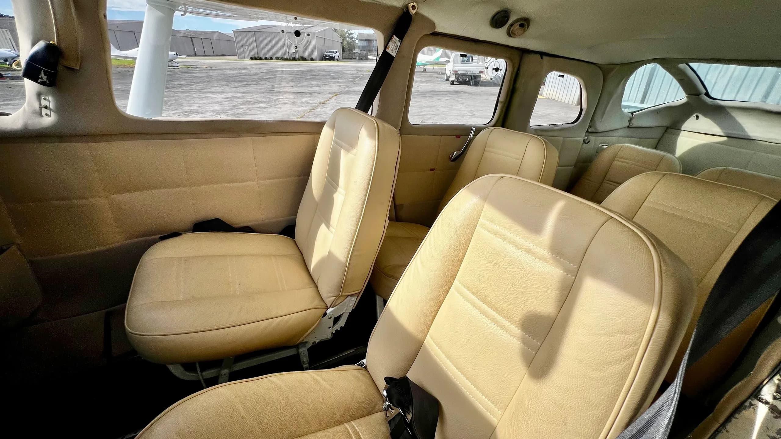 The tan leather interior cabin of a small aircraft, showing multiple passenger seats.