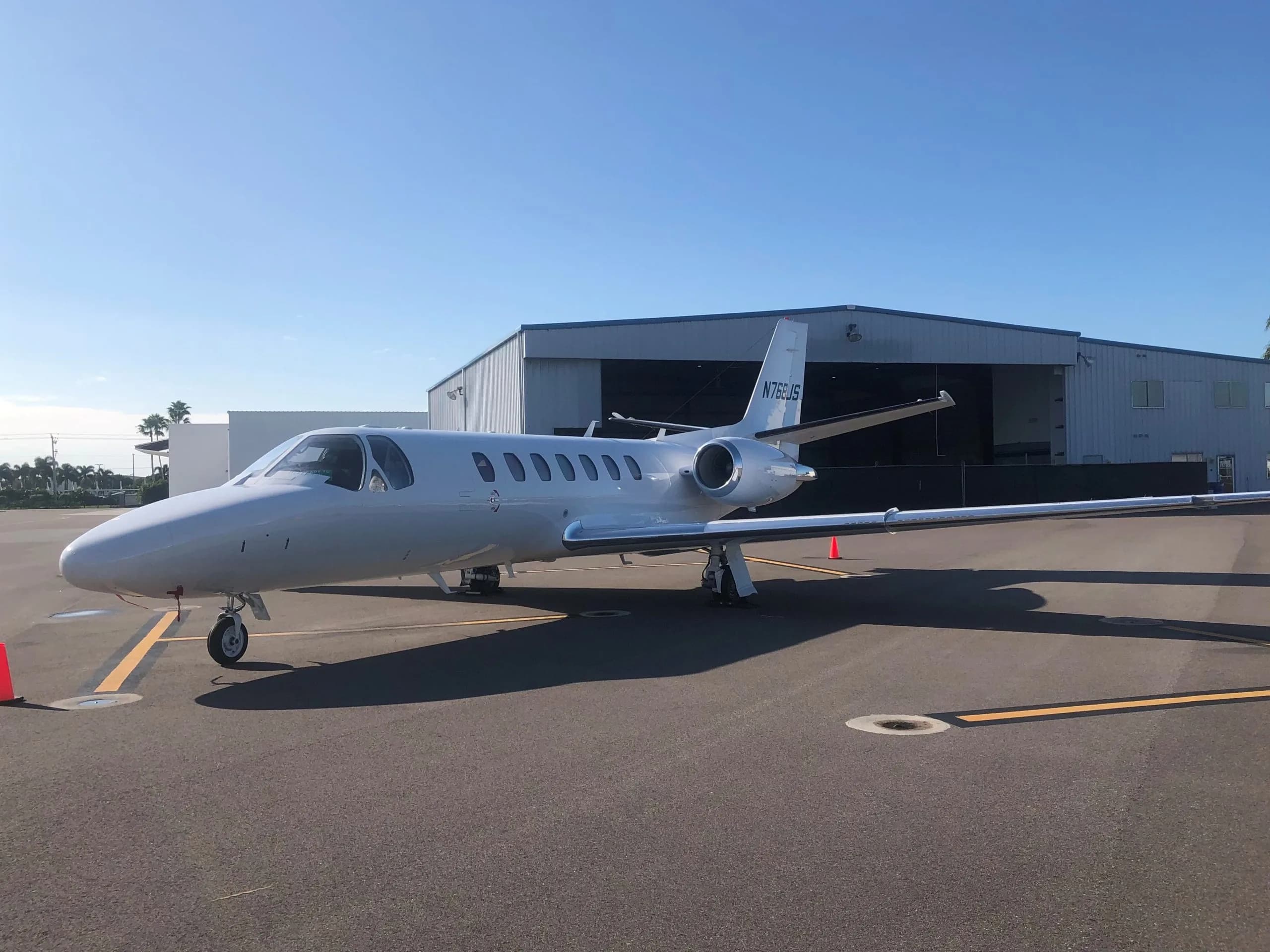 White Cessna Citation CJ3 on the tarmac in front of a hangar.
