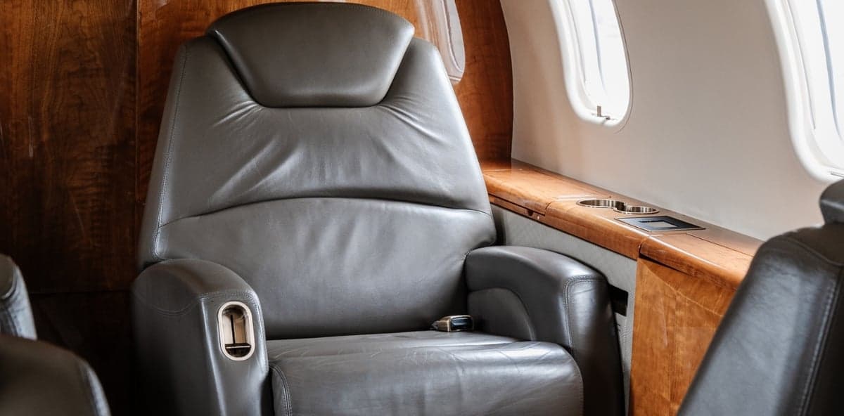 A single leather seat with wood trim and a window.