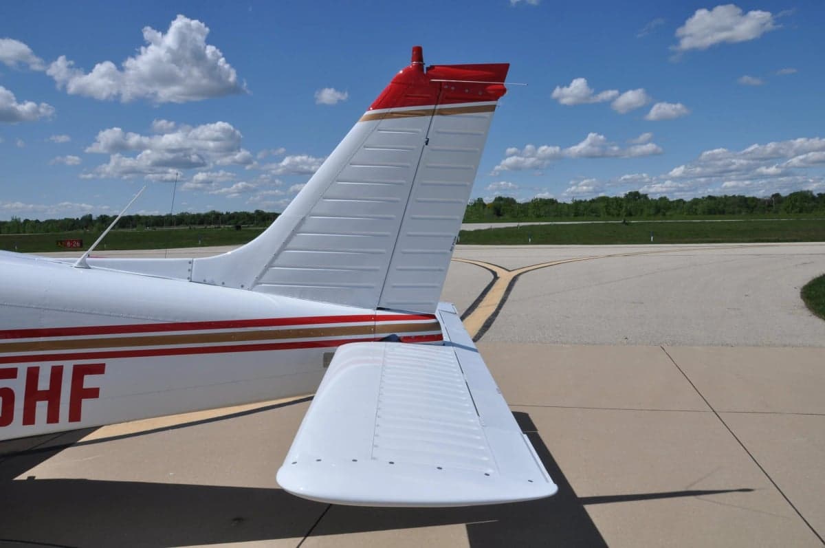 A close-up view of the white aircraft's tail and horizontal stabilizer with red accents.