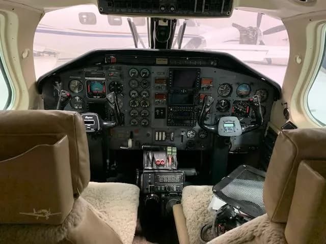 A wide shot of the cockpit from behind the pilot and co-pilot seats, showing the full instrument panel and yokes.
