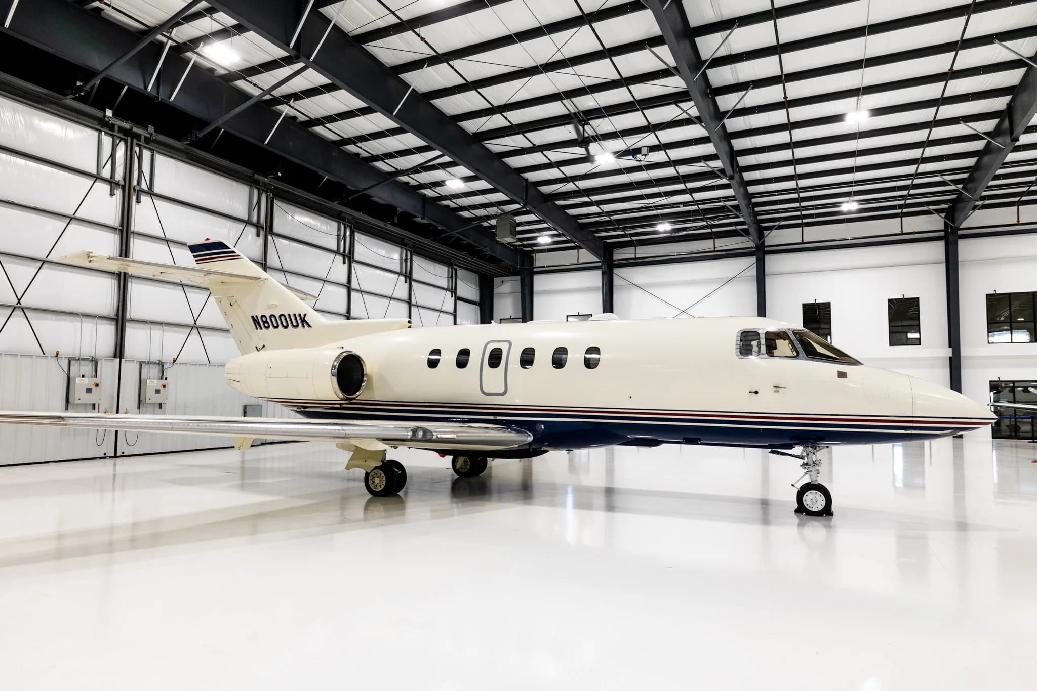 A side view of the N800UK business jet parked inside a brightly lit hangar, showing more of the interior.