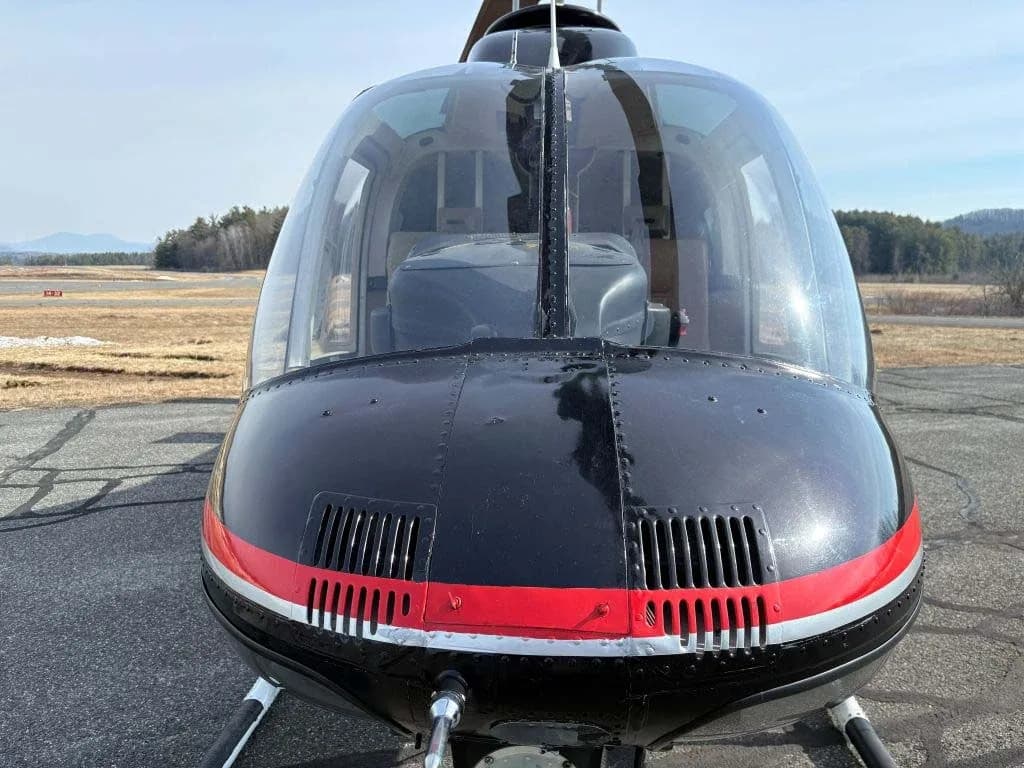 A front view of the black and red nose of a helicopter with its large clear cockpit canopy.