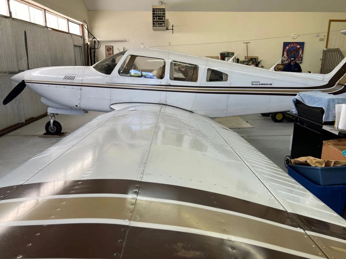 A Piper Turbo Arrow III aircraft with tail number N2164U parked inside a hangar.