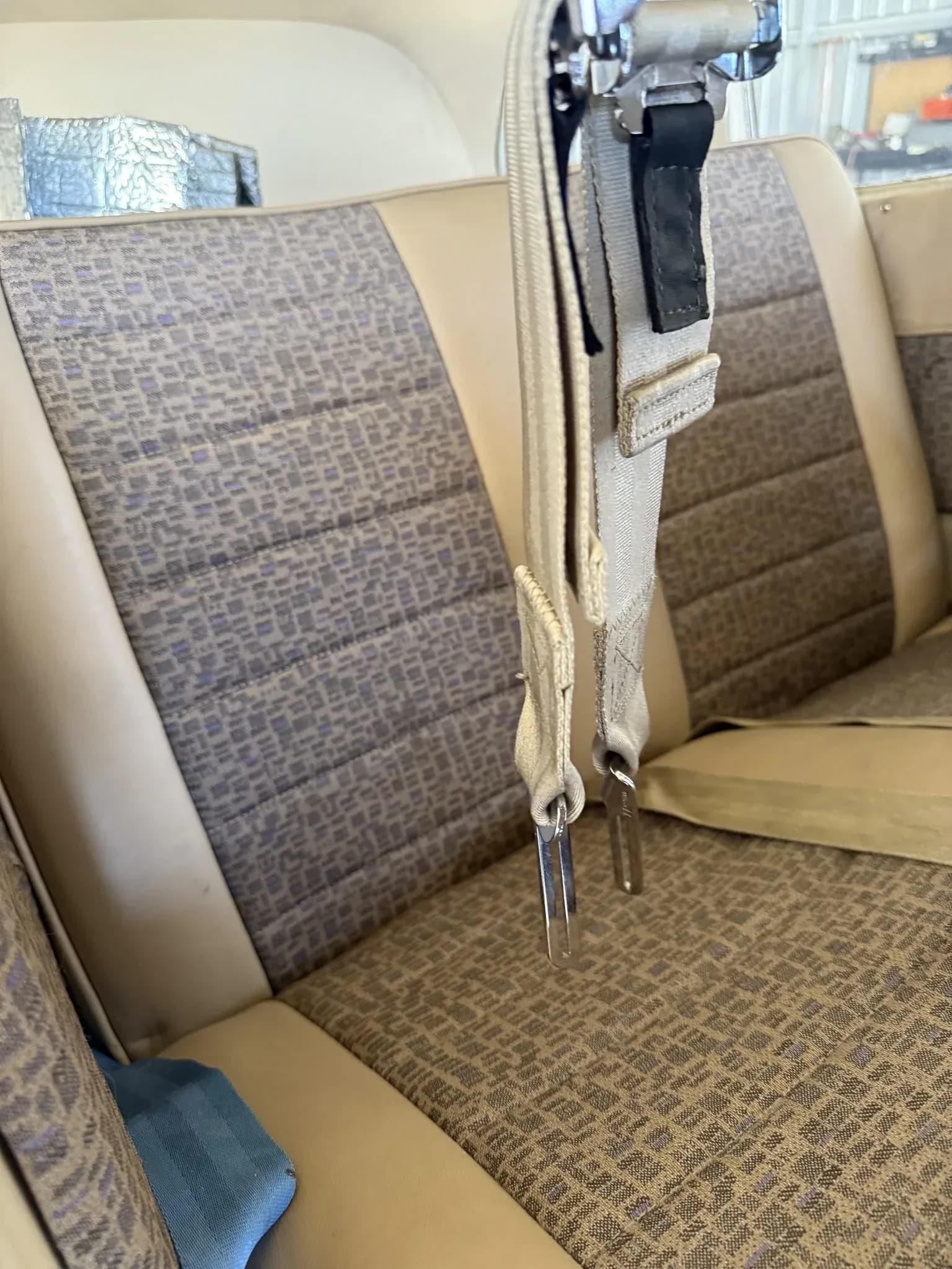 Close-up of the beige and patterned rear passenger seats inside the aircraft cabin.
