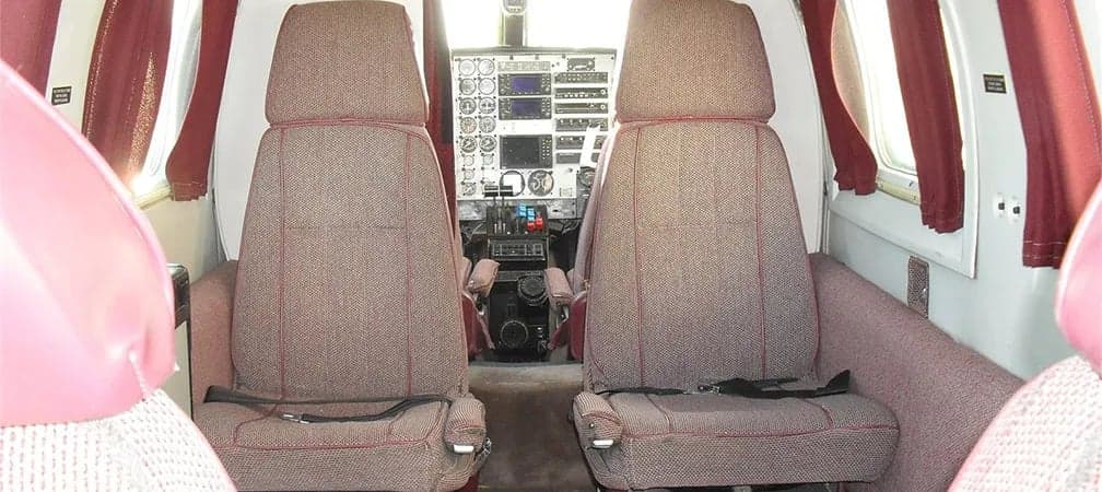 Aircraft interior with forward-facing seats and cockpit view.