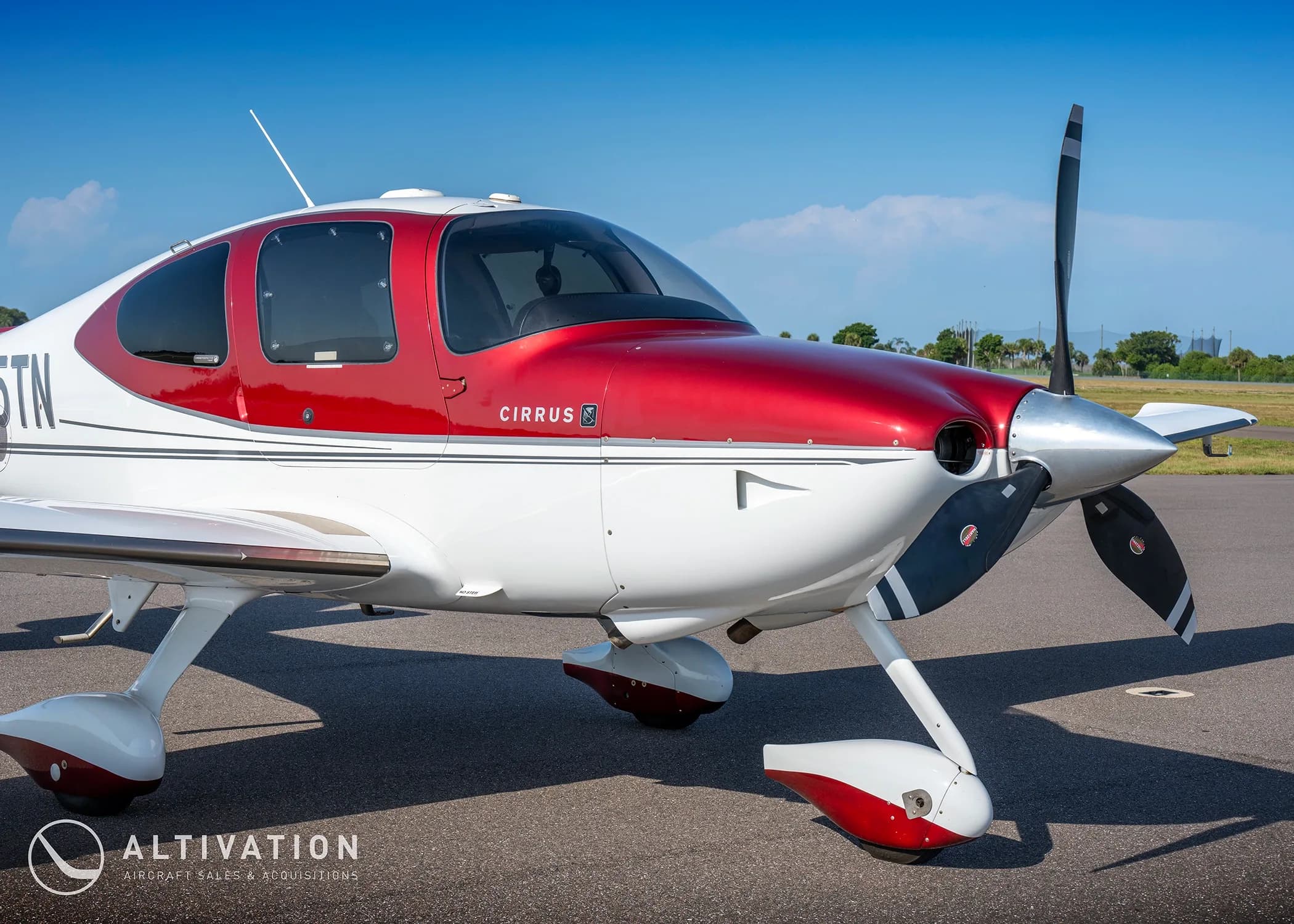 A close-up front view of the propeller and nose of a red and white Cirrus SR22T aircraft (N225TN).