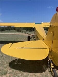 Close up of the tail and landing gear of a yellow Cubcrafters aircraft.