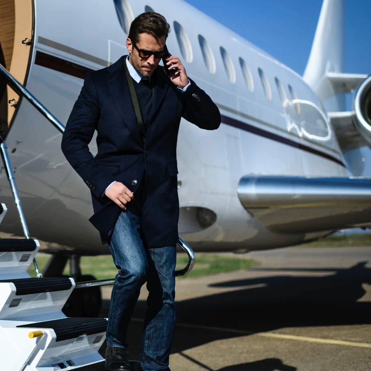 A man exits a white private jet on the tarmac.