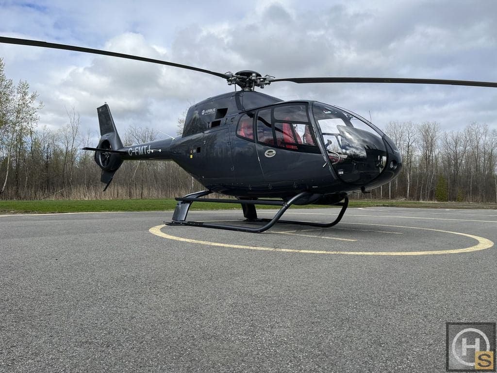 An Airbus helicopter, registration C-FMTJ, is parked on a helipad.