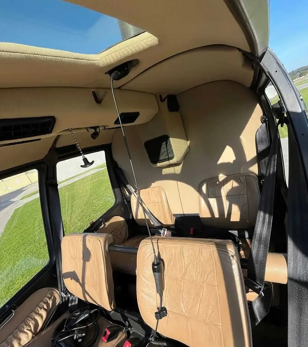 A wide-angle view of the tan leather interior cabin seats of a helicopter.
