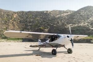 N864G aircraft on a beach with mountains in the background.