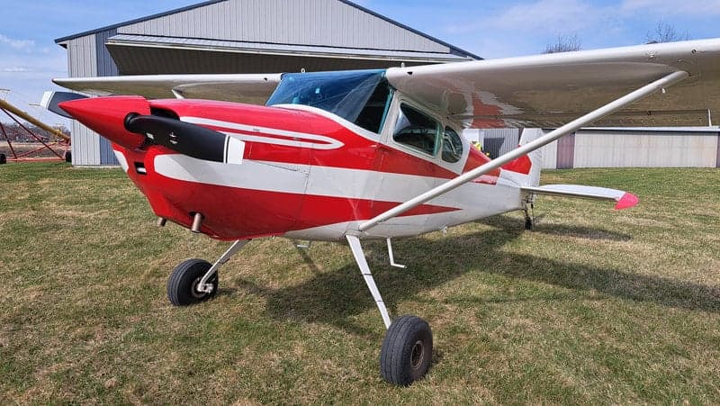 Front view of a red and white Cessna aircraft parked on a grassy field.