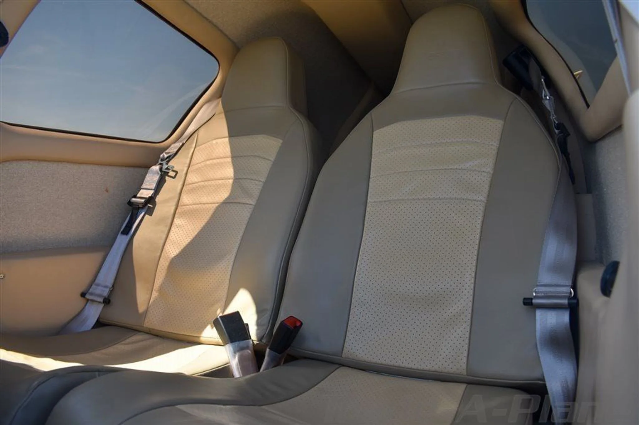 The interior cabin of the Cessna 400 shows two tan leather seats with seatbelts.