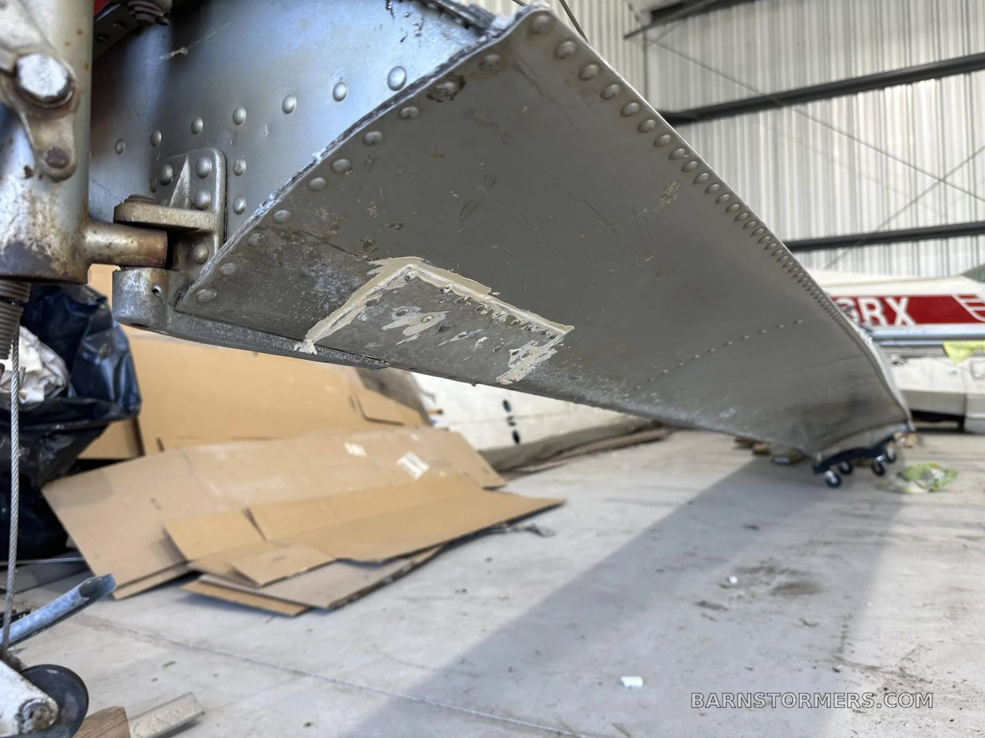 A close-up view of the underside of an aircraft float shows rivets and a repair patch.
