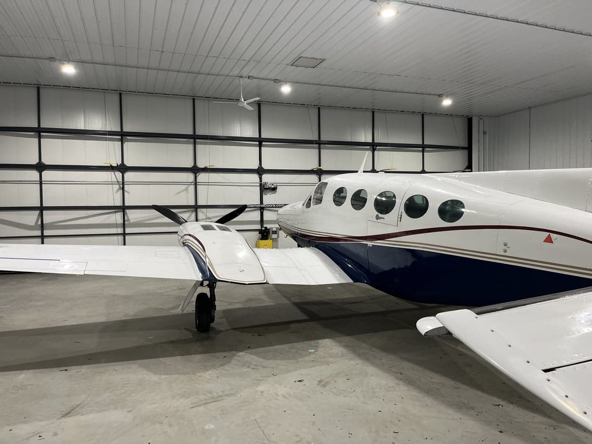 A white and blue twin-engine aircraft is parked in a hangar.