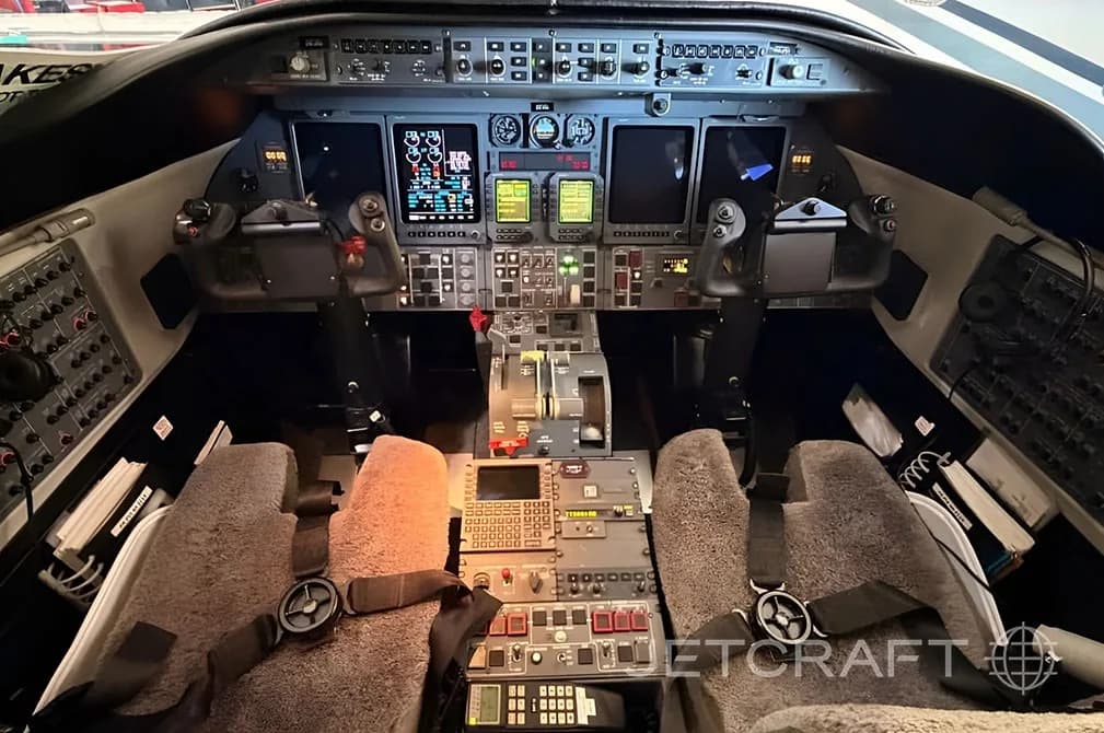 The cockpit of a business jet with multiple digital displays and control yokes.