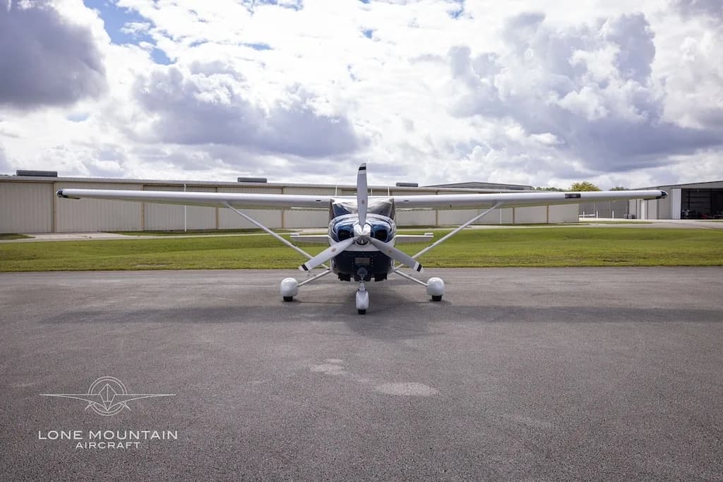 A head-on view of the white and blue Cessna 182 Skylane aircraft, N510SL, parked on an airfield.