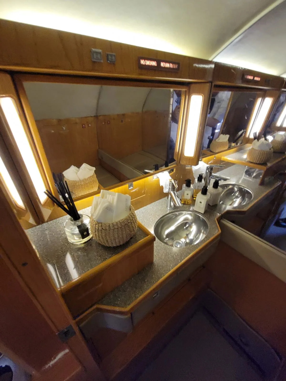 Aircraft lavatory interior with sinks and mirrors.