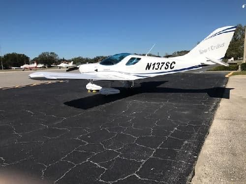 A white Sport Cruiser aircraft with tail number N137SC parked on the tarmac.