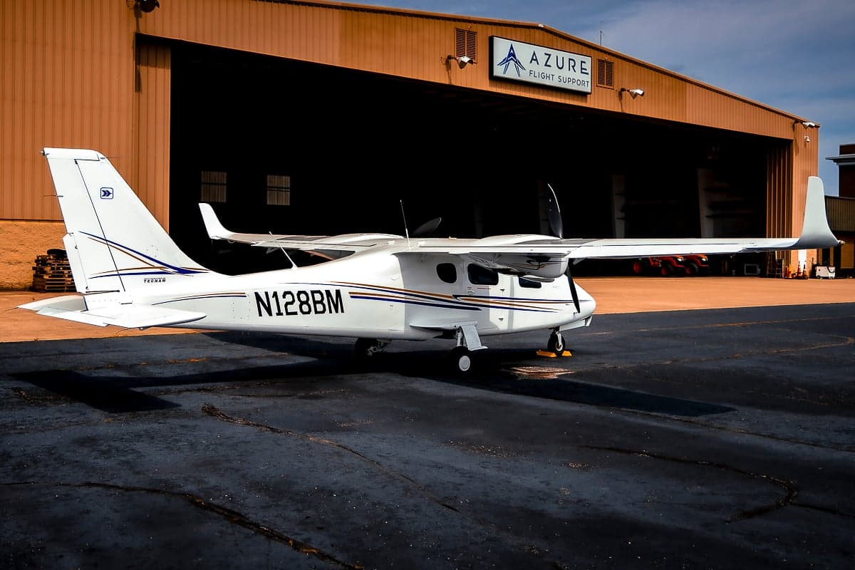 A Tecnam P2006T with registration N128BM is parked in front of an Azure Flight Support hangar.