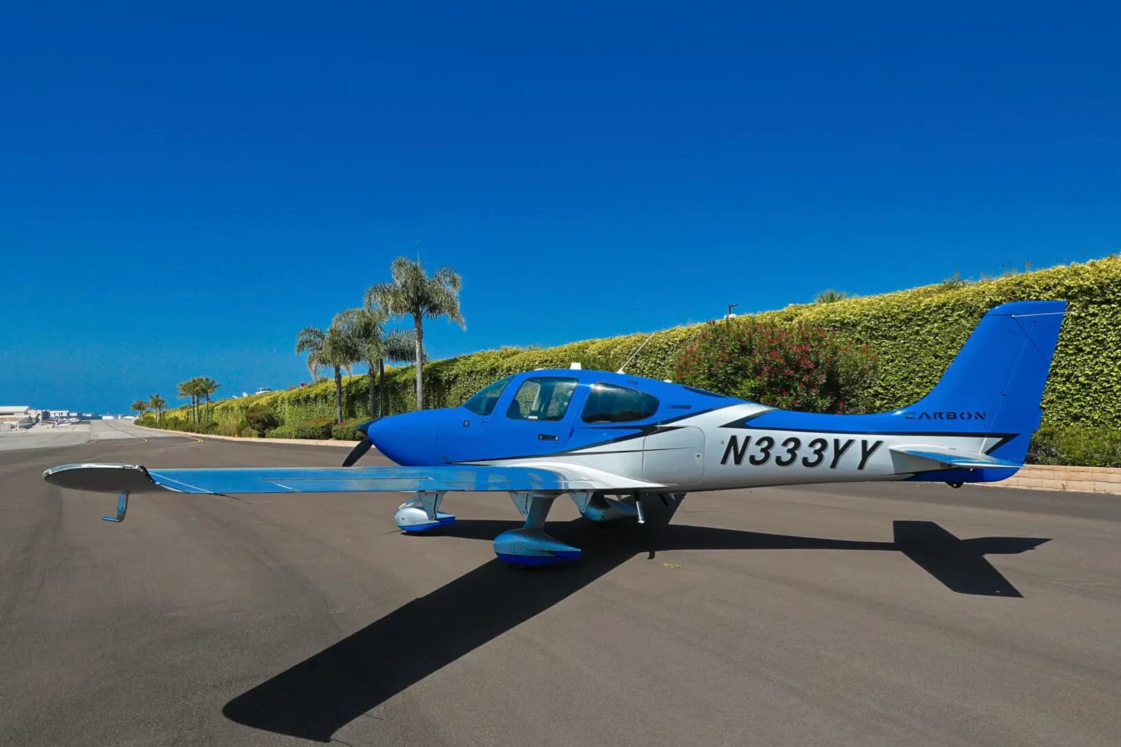A three-quarter front view of the blue and silver Cirrus SR20 aircraft N333YY parked on an asphalt ramp.