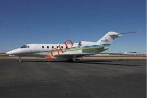 A white jet aircraft with blue and green stripes is parked on the tarmac with the word SOLD overlaid.