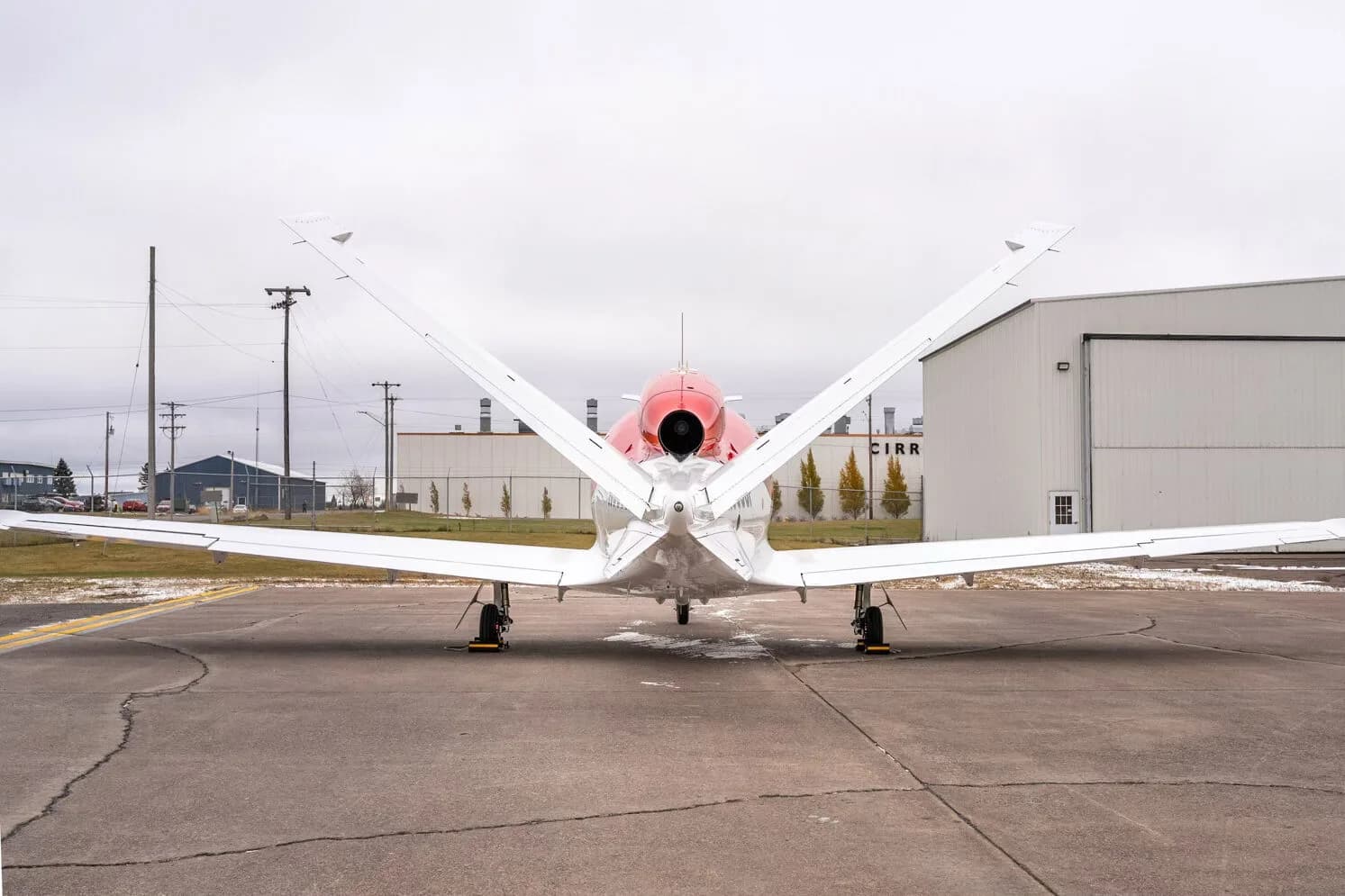Rear view of a red and white Cirrus Vision Jet with its V-tail.