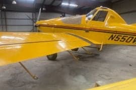A yellow agricultural aircraft with tail number N550F is parked in a hangar.