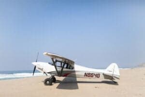 N864G aircraft on a beach with the ocean in the background.