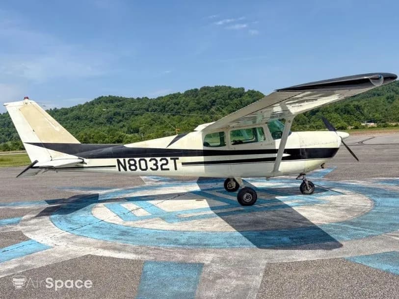 Side view of a white and black Cessna 172 N8032T parked on an airfield.