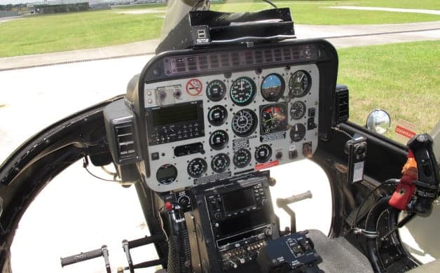 Another view of the helicopter cockpit, highlighting the instrument panel and cyclic stick.
