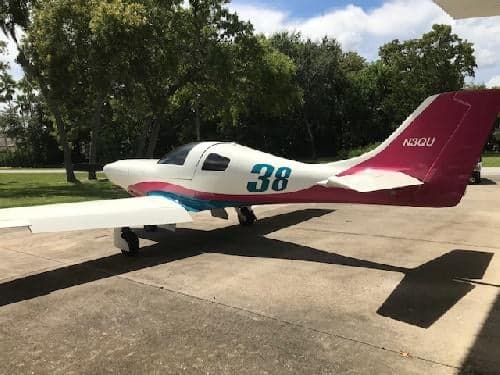 A white and pink aircraft with the number 38 on the side is parked on a concrete pad.