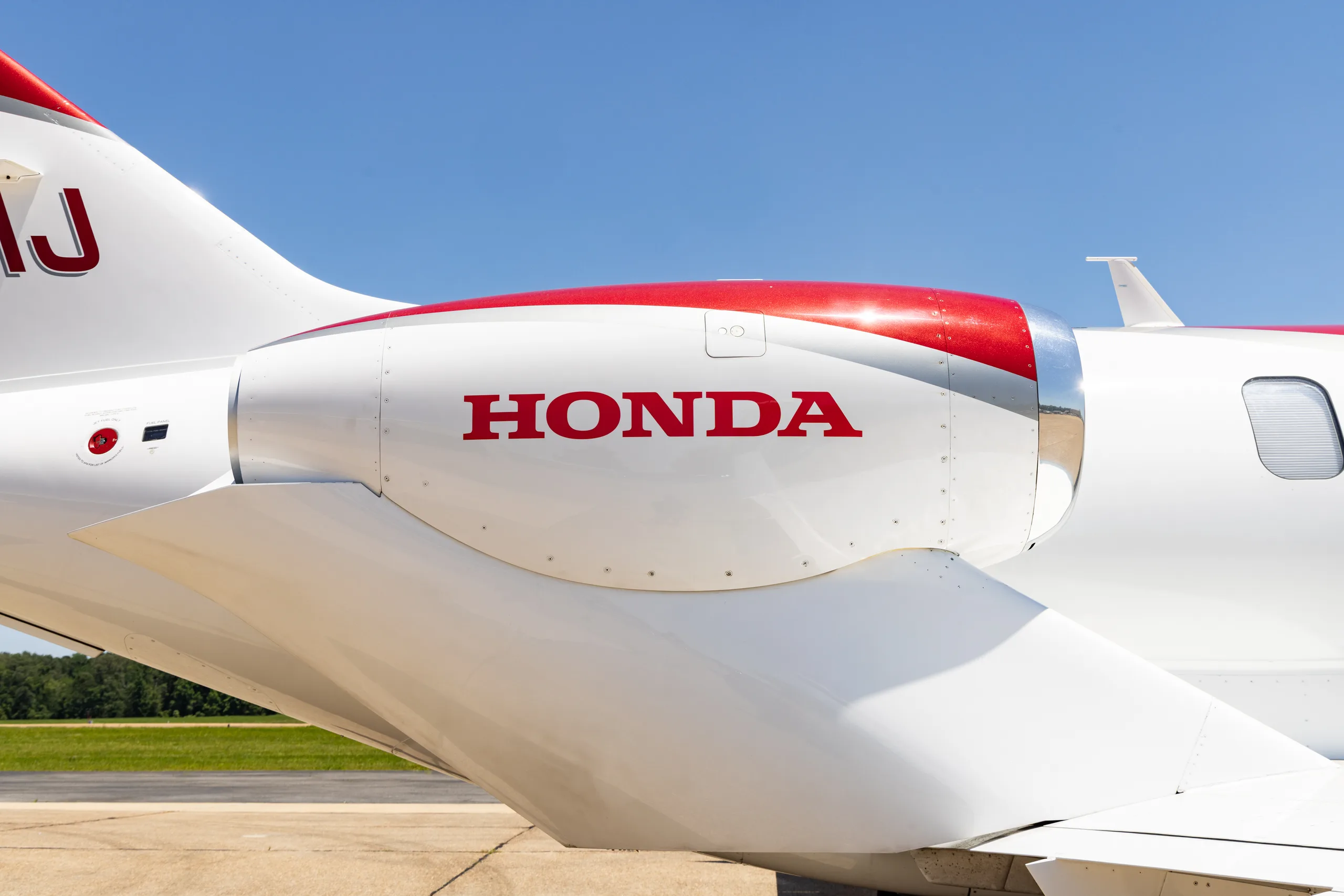 Close-up view of the red and white engine nacelle of a HondaJet HA-420 (N30HJ), featuring the "HONDA" logo.