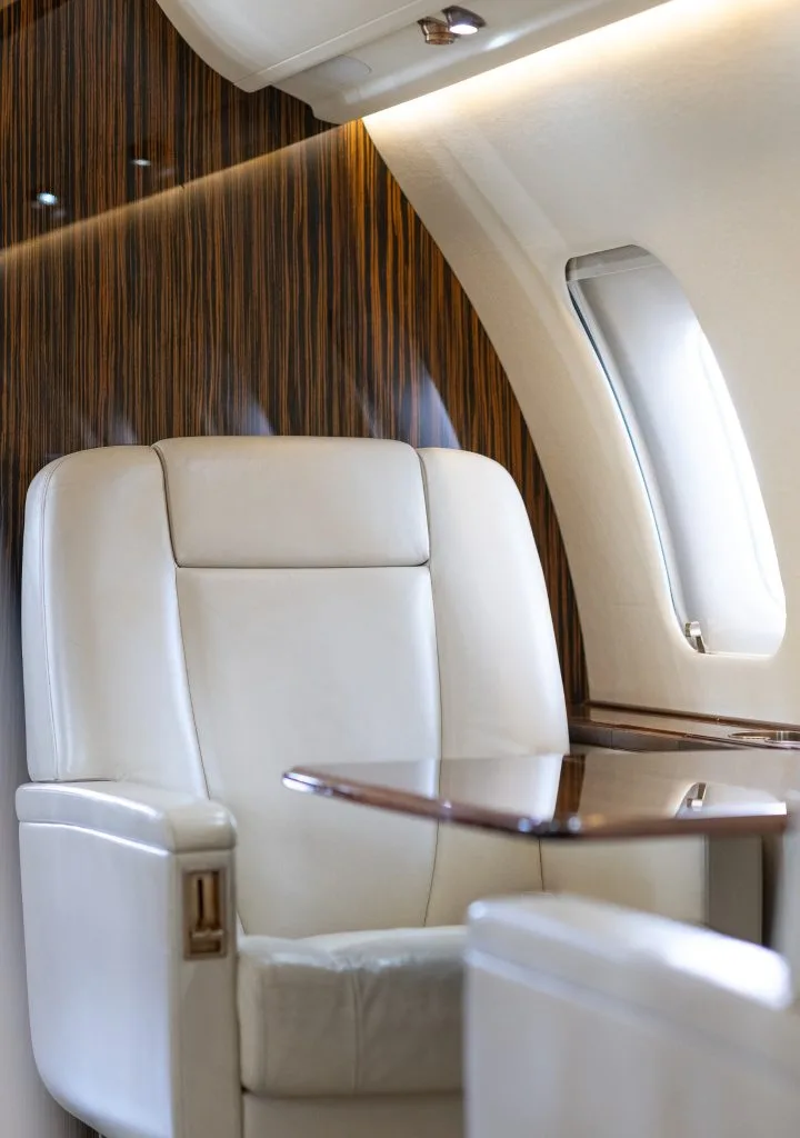 A close-up of a cream leather seat next to a window in the aircraft's cabin.